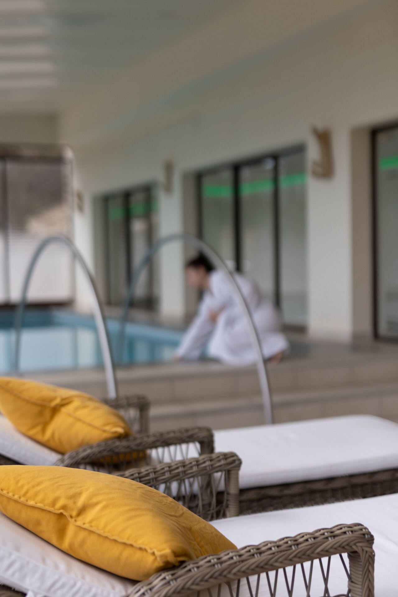 A poolside area with lounge chairs and a person in the background.
