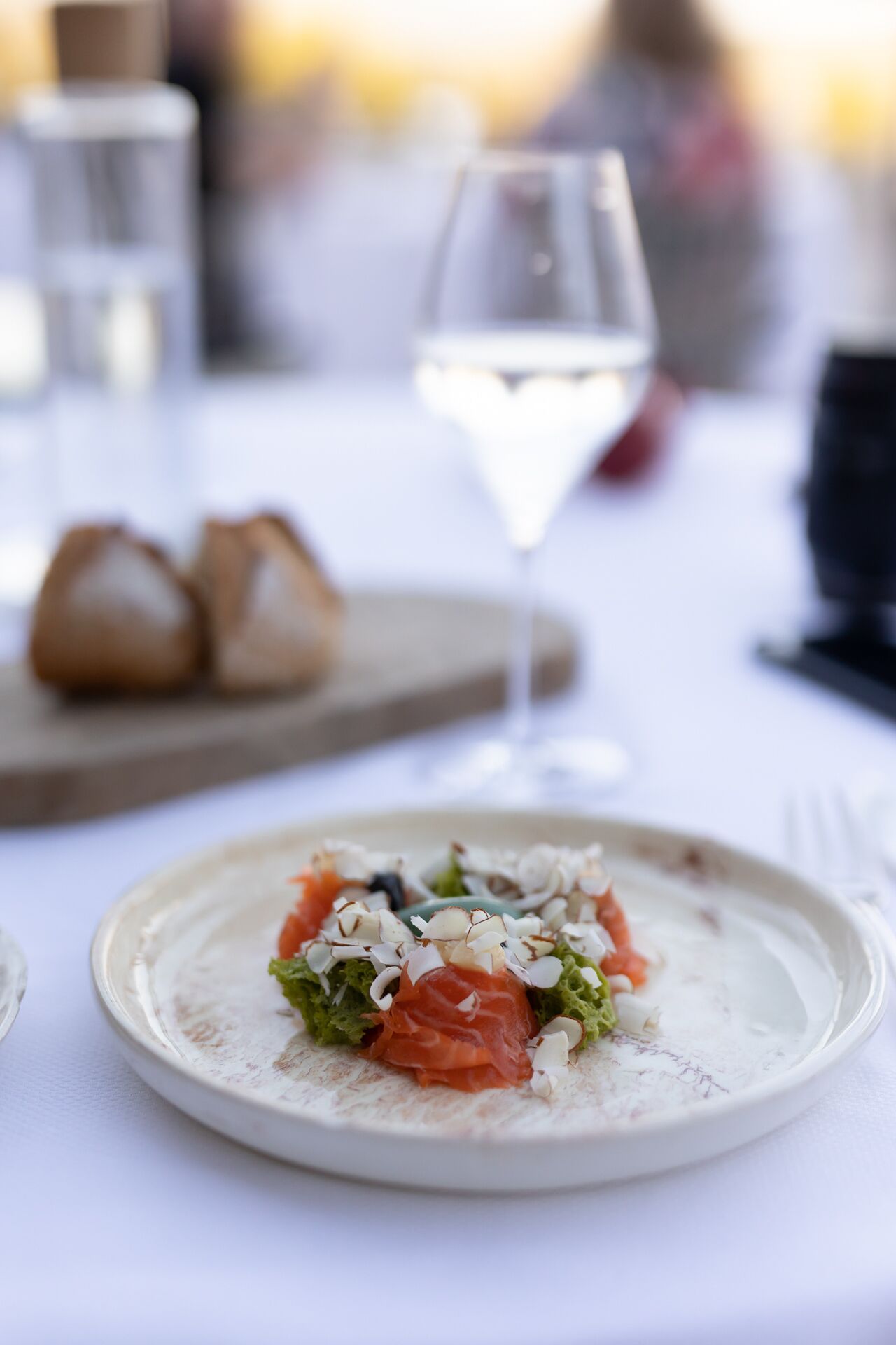 Un plato de comida con una copa de vino blanco sobre una mesa.