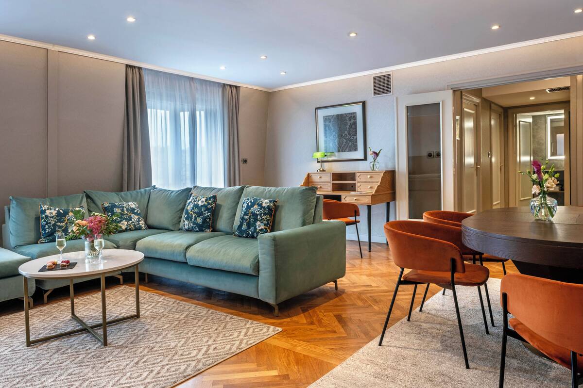 Una sala moderna con sofá, mesa de centro y sillas, una mesa de comedor y un cuadro en la pared.
