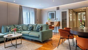 A modern living room with a sofa, coffee table, and chairs, a dining table, and a painting on the wall.
