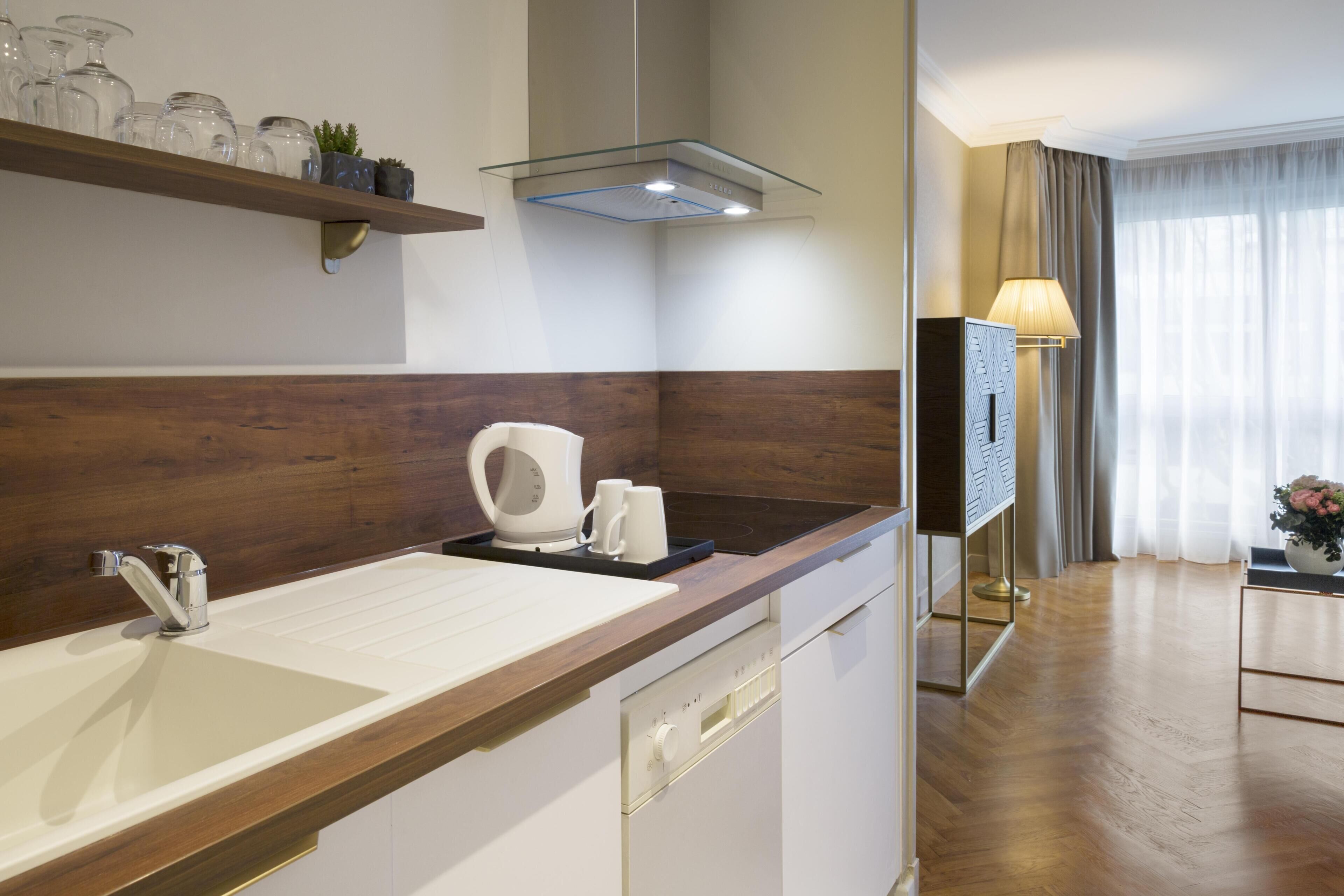 Un baño de hotel moderno con un tocador de madera, un lavamanos, una cafetera y un espejo.
