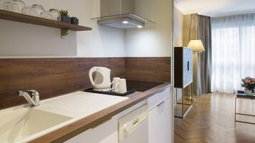 Un baño de hotel moderno con un tocador de madera, un lavamanos, una cafetera y un espejo.