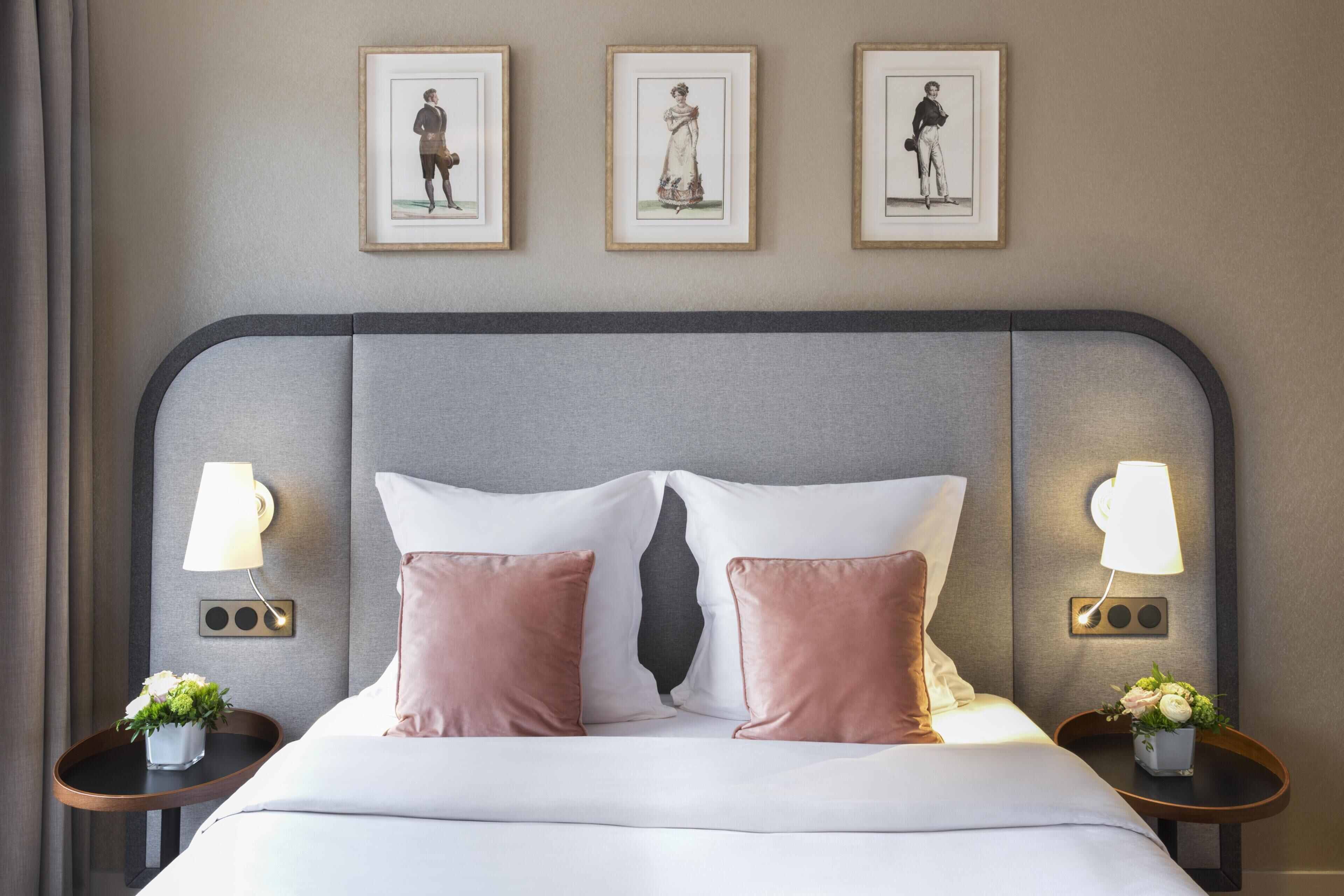A hotel room with a bed, two bedside tables with lamps, and three framed pictures on the wall.
