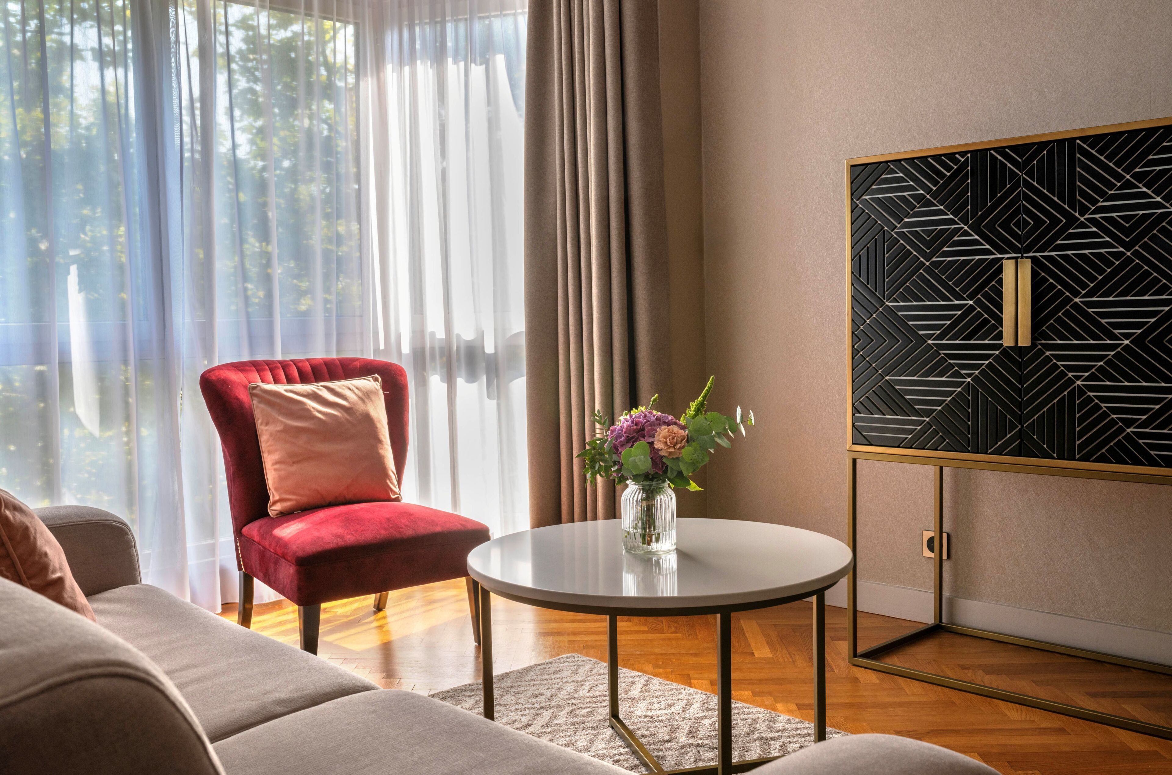 Un salon moderne avec un fauteuil rouge, une table basse ronde et un élément décoratif mural.