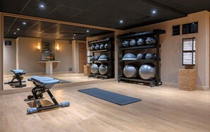 A gym with exercise equipment, a yoga mat, and a wall with exercise balls.