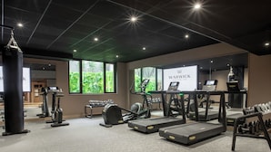Un gimnasio con cintas de correr, máquinas elípticas y equipo de pesas.
