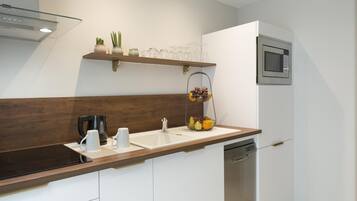 Une cuisine moderne dotée d’un plan de travail en bois, d’un lave-vaisselle encastré, d’un four à micro-ondes et d’un panier à fruits.