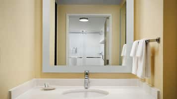 Un baño con un lavamanos blanco, un espejo y un perchero para toallas.