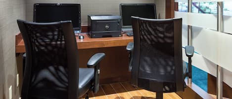 Un espacio de trabajo con dos sillas de oficina, dos monitores e impresora sobre un escritorio.