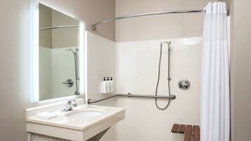 A modern bathroom with a bathtub, a shower, a vanity with a mirror, and a towel rack.