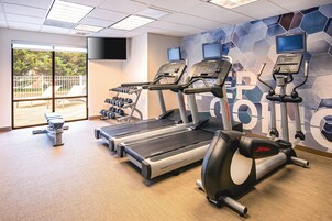 Un gimnasio con cintas de correr, elípticas y mancuernas.