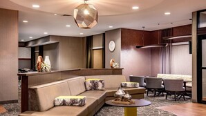 Un moderno vestíbulo de hotel con un sofá curvo, una mesa redonda y un comedor con sillas.