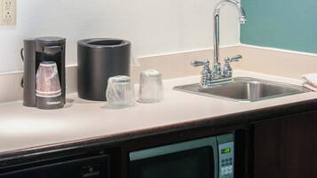 Una kitchenette equipada con cafetera, microondas y lavabo.