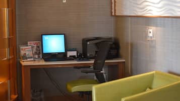 Un petit bureau comprenant un bureau, un ordinateur, une chaise et une poubelle.