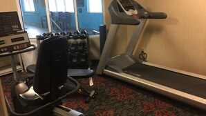 Un gimnasio con cinta de correr, banco para pesas y mancuernas.