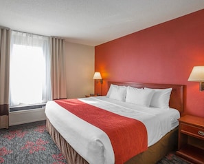 A hotel room with a large bed, a nightstand, a lamp, and a window with curtains. - Comfort Inn & Suites University (Calgary)