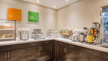 A modern kitchen with a buffet setup, including a coffee station and a refrigerator.
