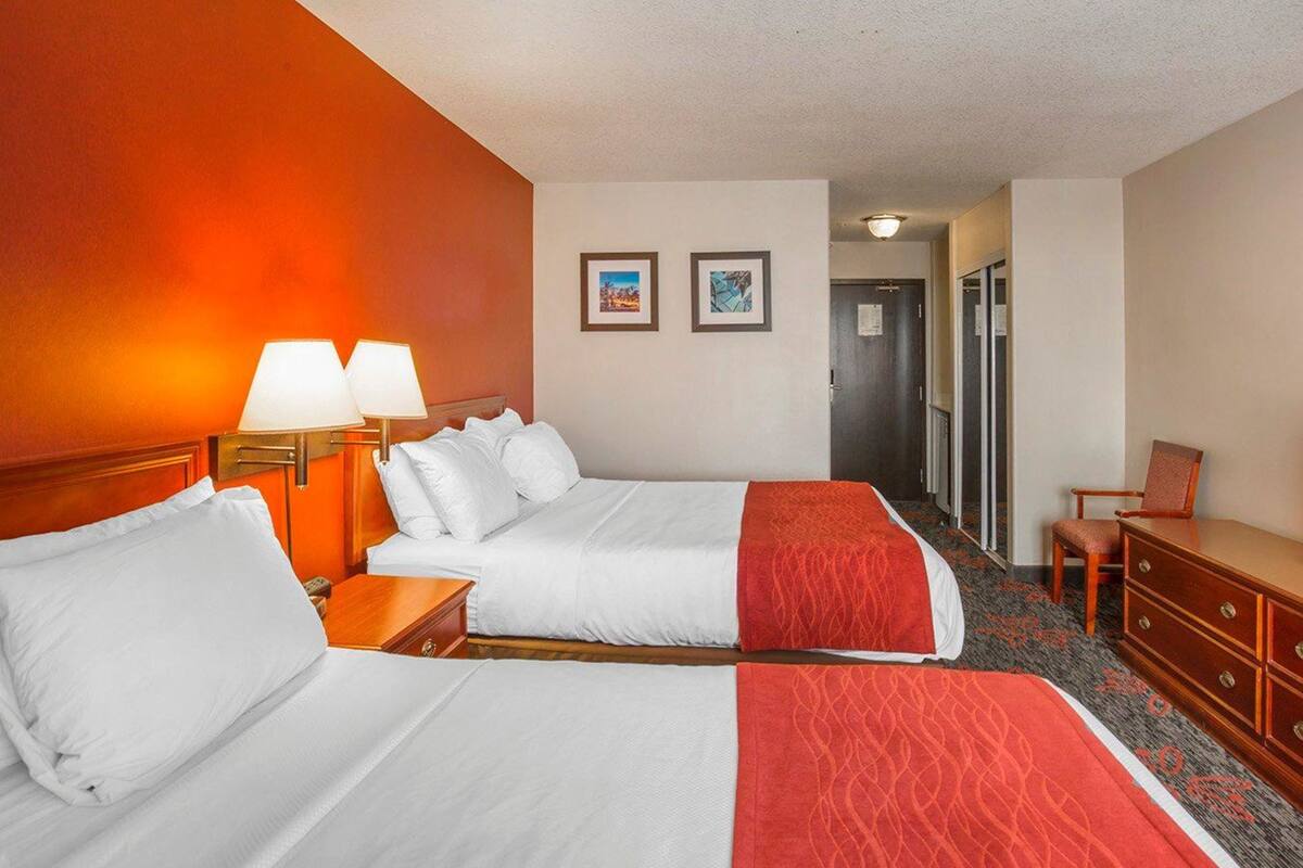 Ett hotellrum med två sängar, en byrå, ett skrivbord och en stol.