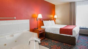A hotel room with a large bathtub, a bed with white linens, two bedside lamps, and a red carpet with a floral pattern.