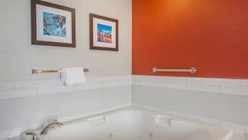 Un bagno con una vasca da bagno bianca, due quadri appesi al muro e una parete di colore rosso.