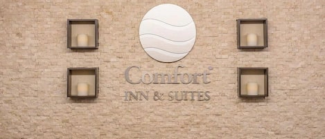 A brick wall with the text 'Comfort INN & SUITES' and four square light fixtures.
