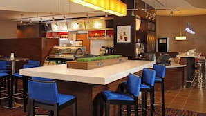 Zona de bar moderna con una barra central, taburetes y un panel de menú.