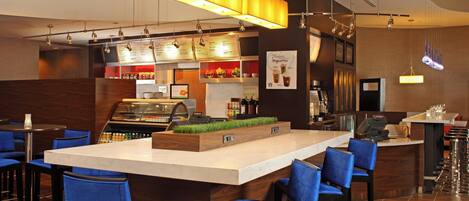 A modern bar area with a central island, bar stools, and a menu board.