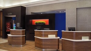 Zona de recepción con diseño moderno, que incluye un mostrador de madera y una pantalla digital.