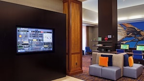 Un vestíbulo de hotel con una pantalla grande mostrando una interfaz GoBoard, una zona de estar con cojines y un mural grande en la pared.