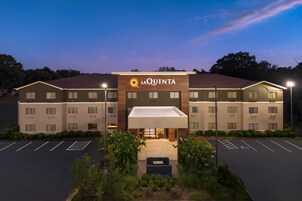 Un hotel con techo plano, entrada cubierta y estacionamiento con espacios delimitados.
