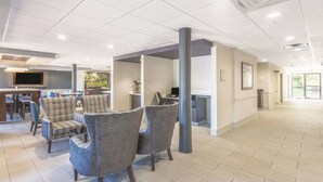 A spacious lobby with a reception desk, seating area, and a large pillar. - La Quinta Inn & Suites by Wyndham Jackson Airport/Pearl (Pearl)