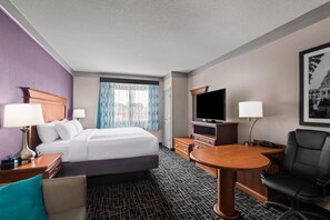A hotel room with a bed, a desk, a TV, a chair, and a lamp. - La Quinta Inn & Suites by Wyndham Jackson Airport/Pearl (Pearl)