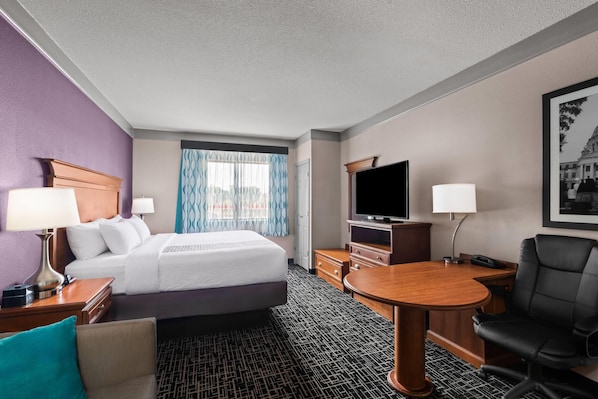 A hotel room with a bed, a desk, a TV, a chair, and a lamp. - La Quinta Inn & Suites by Wyndham Jackson Airport/Pearl (Pearl)