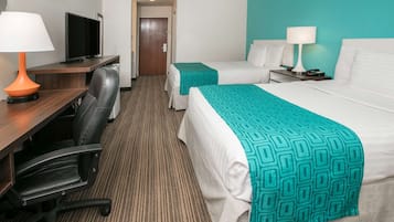 Quarto de hotel com duas camas, uma mesa de trabalho com televisão, uma cadeira e uma porta.