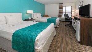 Une chambre d’hôtel avec deux lits, un bureau avec une télévision et un coin salon avec une lampe.