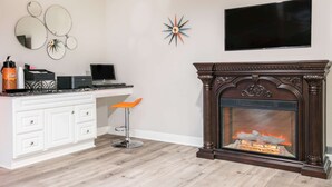 Un salon moderne avec une cheminée, un téléviseur fixé au mur et un bureau avec une chaise.