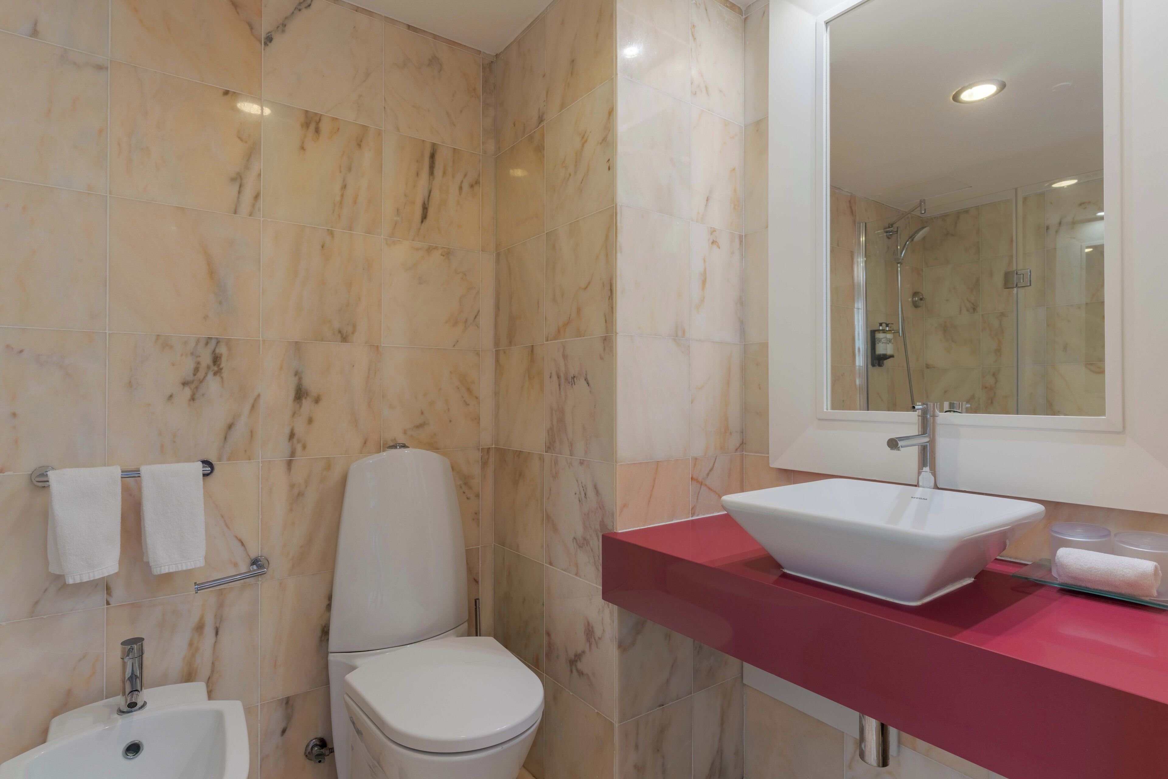 A bathroom with a white toilet, a white sink, and a glass shower enclosure.