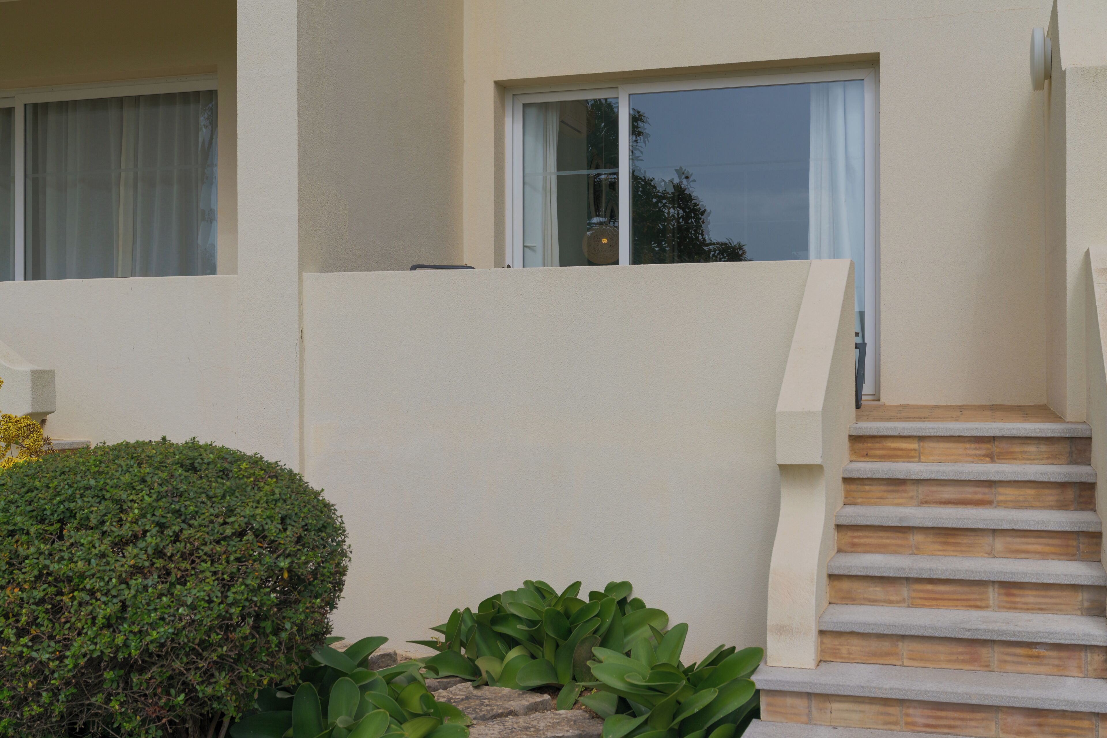 Un bâtiment moderne avec un escalier menant à une porte dotée d’un panneau de verre.