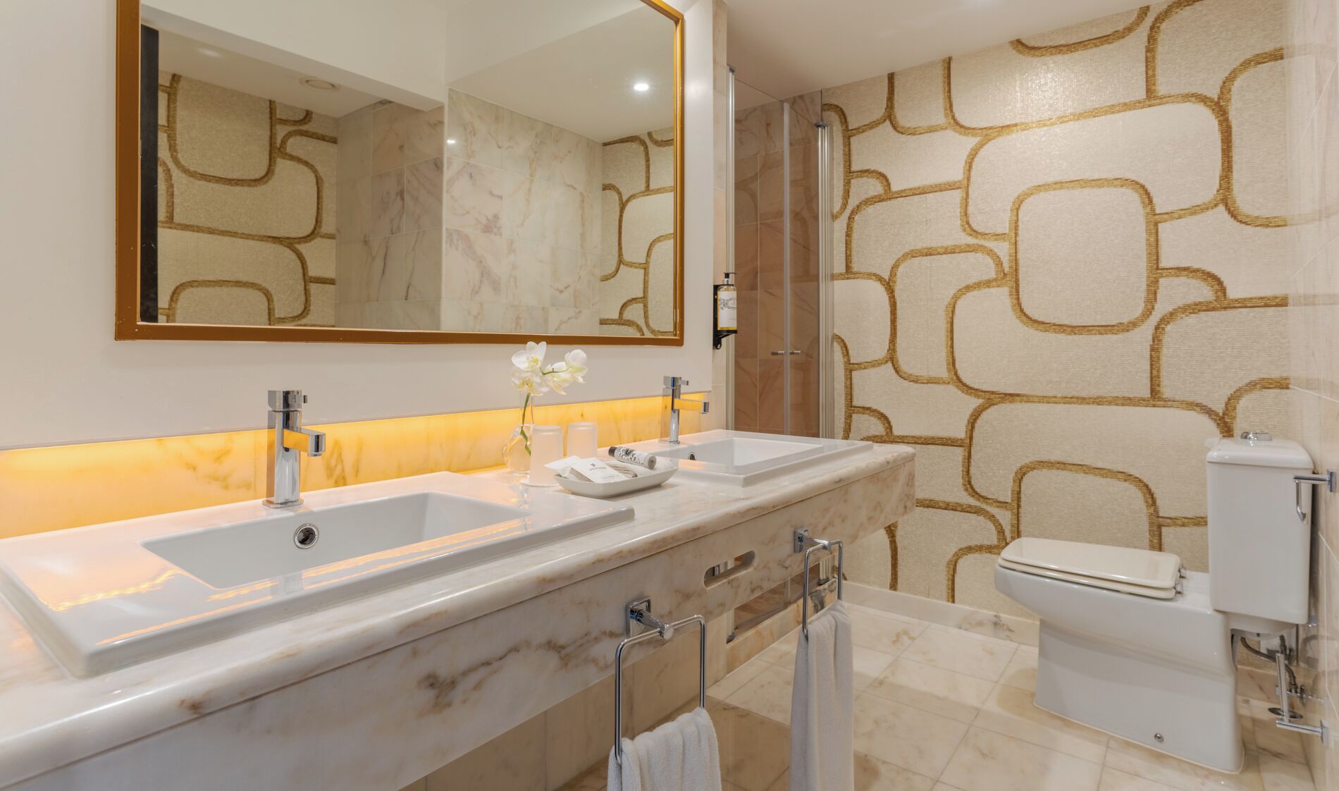 A modern bathroom with two sinks, a toilet, and a shower.