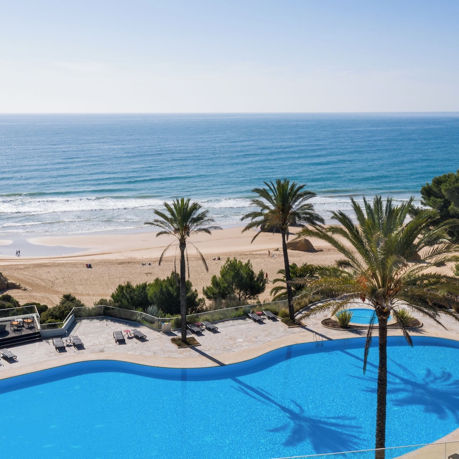 A resort with a swimming pool, beach, and ocean views.