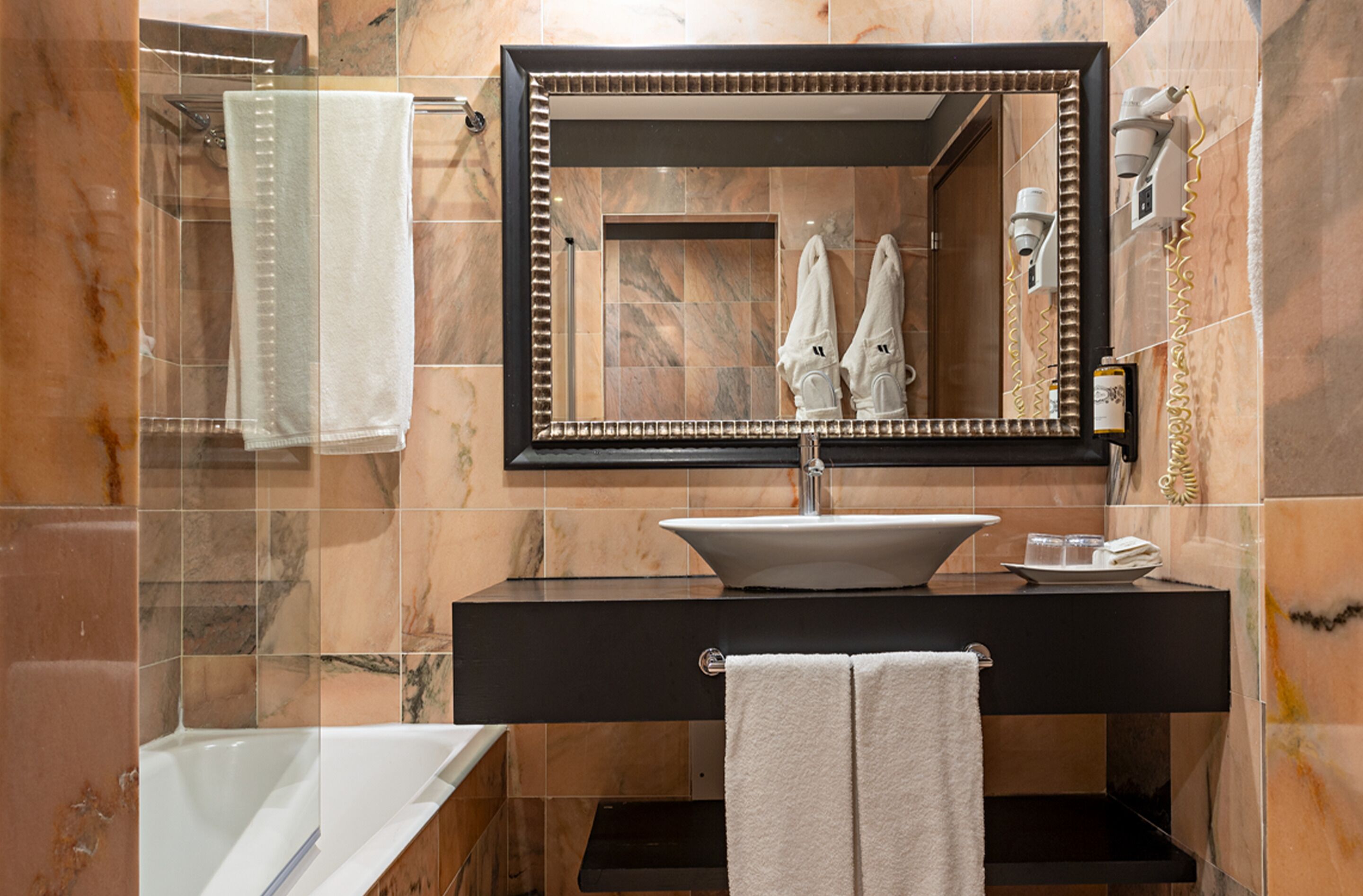 A modern bathroom with a large mirror, a sink, a bathtub, and a towel rack.