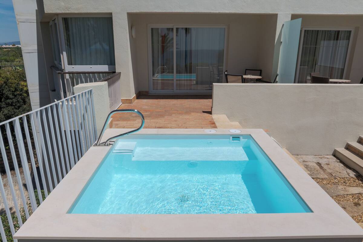 Ein rechteckiger Pool mit einer Metallleiter, umgeben von einem weißen Zaun.