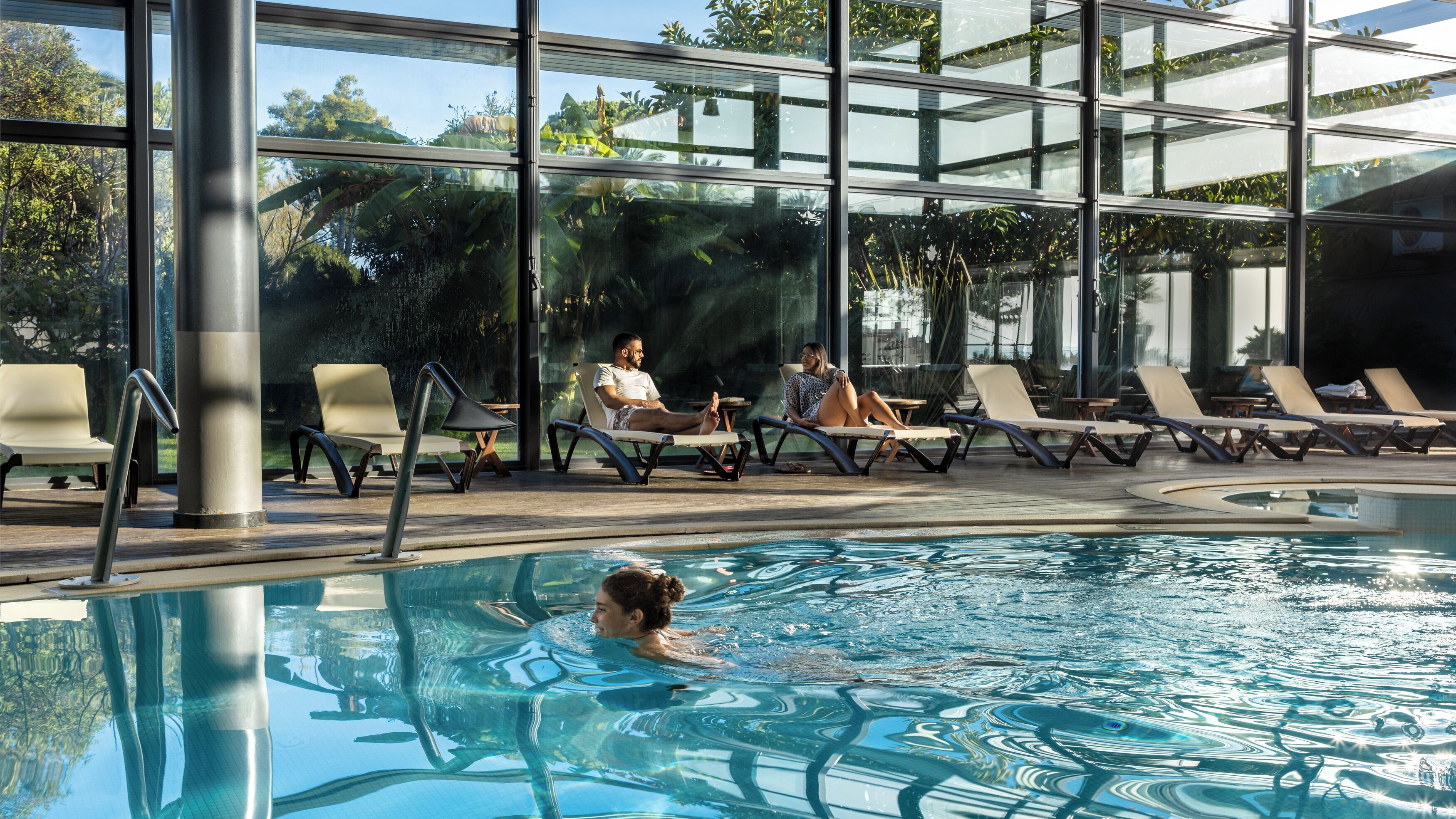 Un espace piscine avec des chaises longues et une personne qui nage.