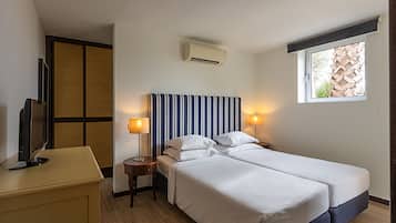 Habitación de hotel con dos camas, televisión, escritorio y ventana con vista a una estructura de madera.