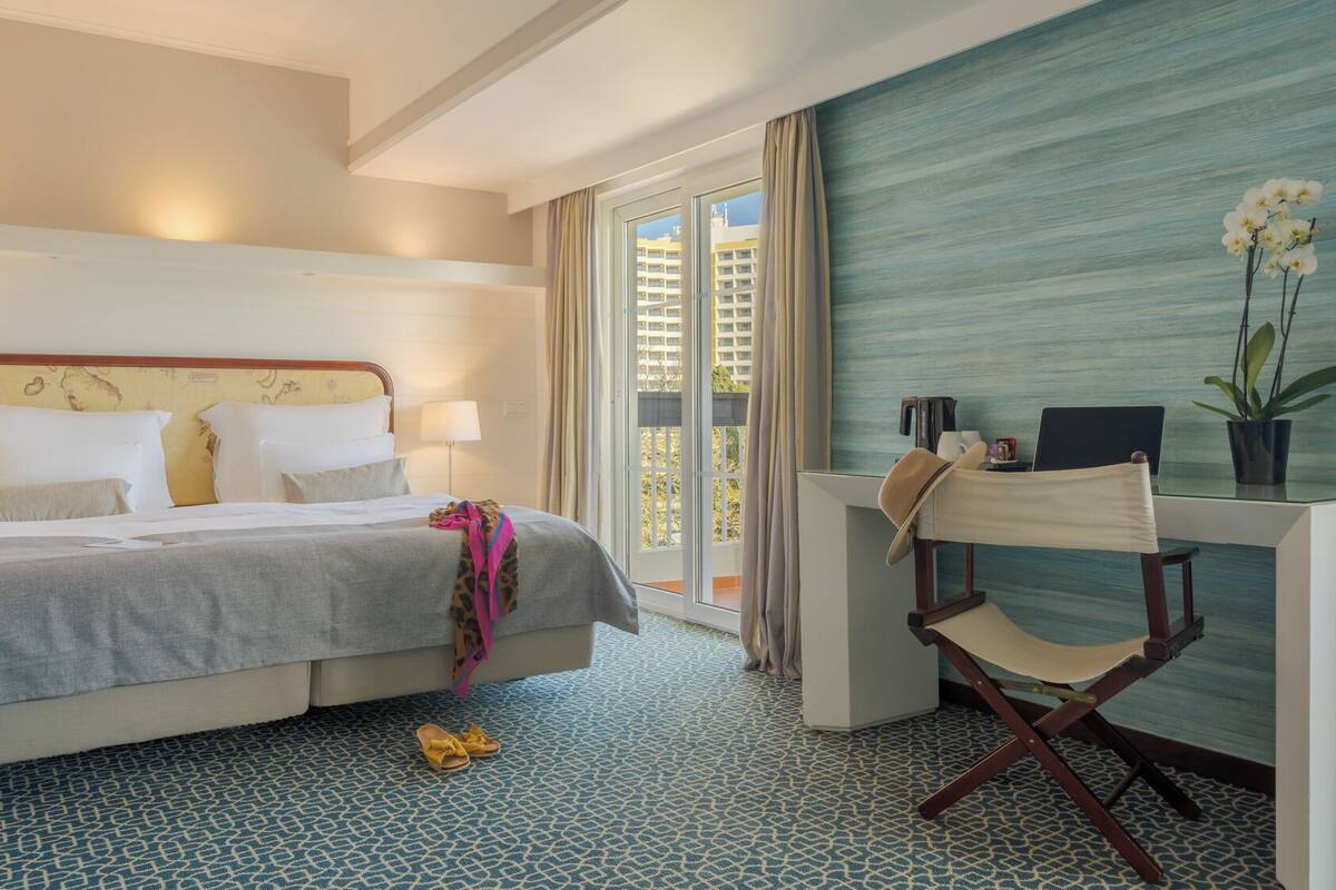 Ein Hotelzimmer mit Bett, Schreibtisch und Blick auf die Stadt.