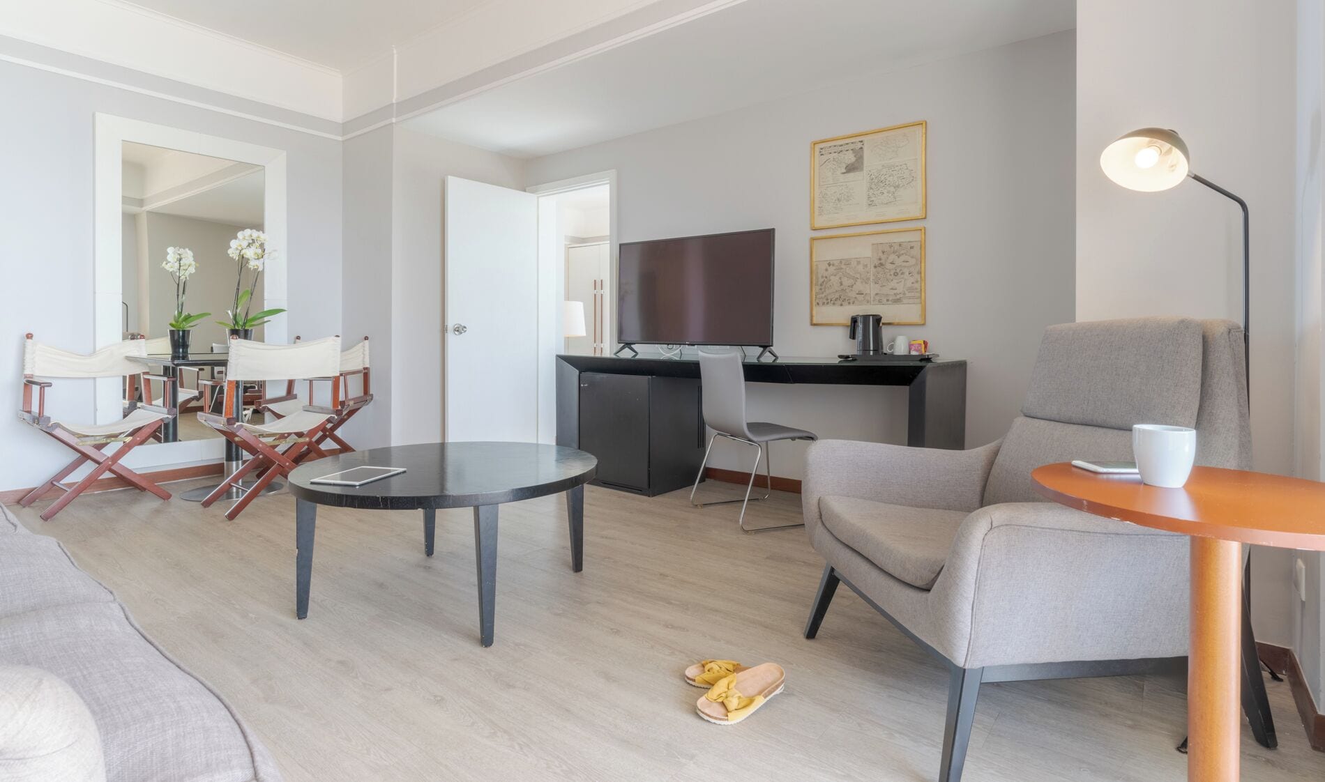 A modern living room with a sofa, a dining table, a kitchen area with a TV, and a coffee table.