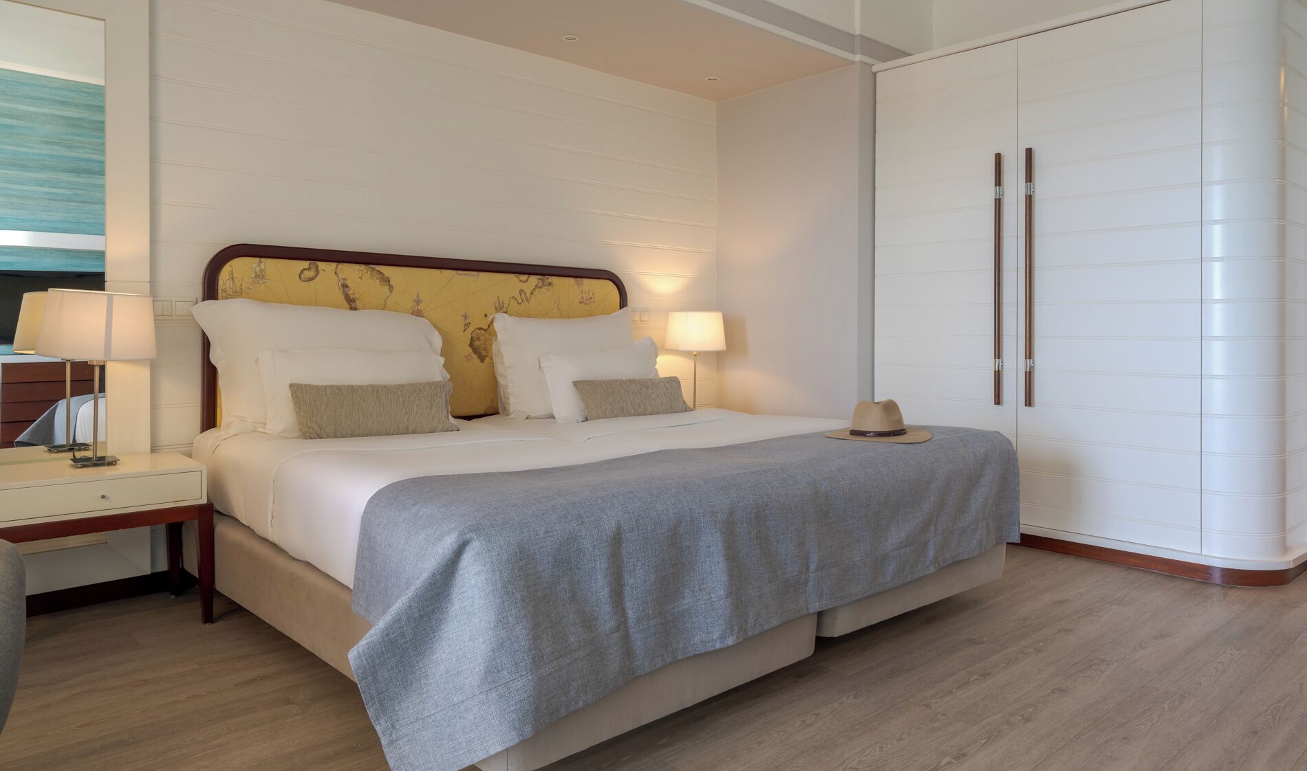 Una habitación de hotel con cama, mesitas de noche, armario y lámpara.