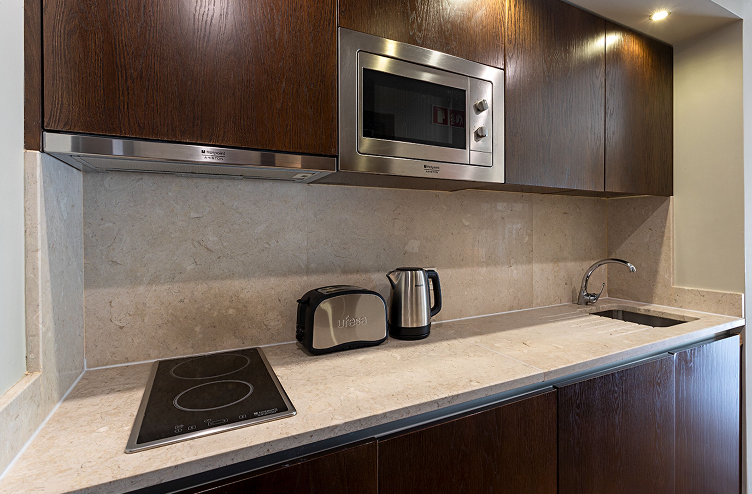 A kitchen with a built-in microwave, toaster, and kettle on the countertop.