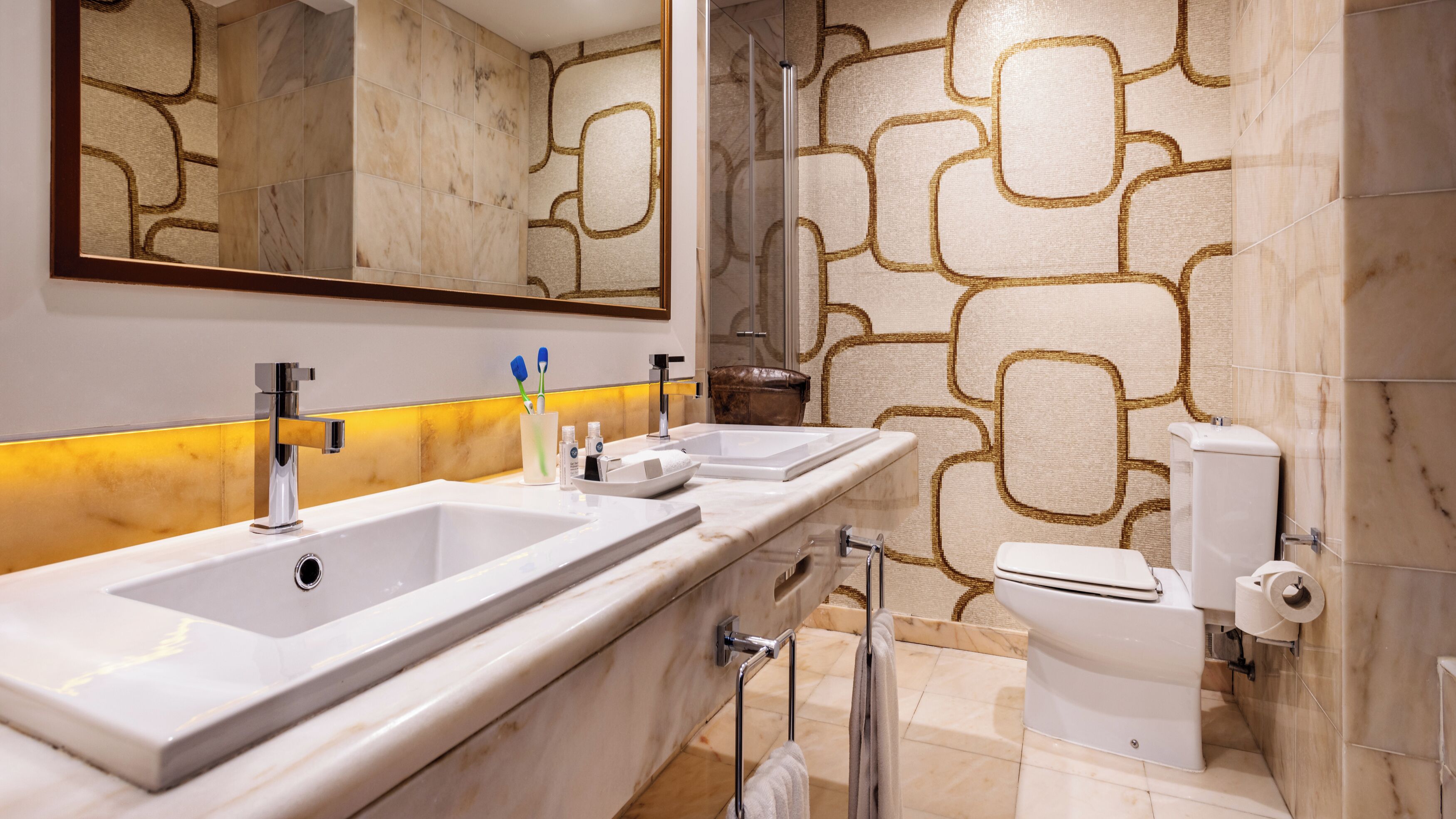 Un baño moderno con dos lavamanos, inodoro y ducha.