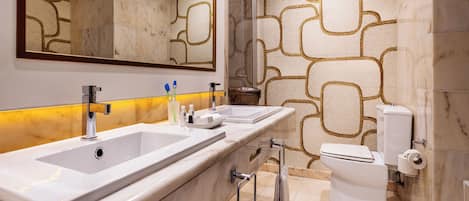 Un baño moderno con dos lavamanos, inodoro y ducha.
